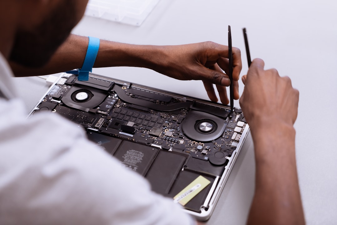 Technician hands-on repairing a laptop, diagnostic tools nearby